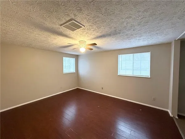 an empty room with wooden floor and windows