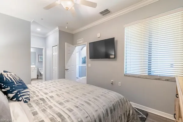 a bedroom with a bed a tv and wooden floor