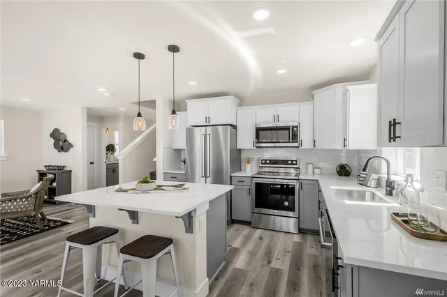 a kitchen with stainless steel appliances kitchen island granite countertop a stove a sink a dining table and chairs