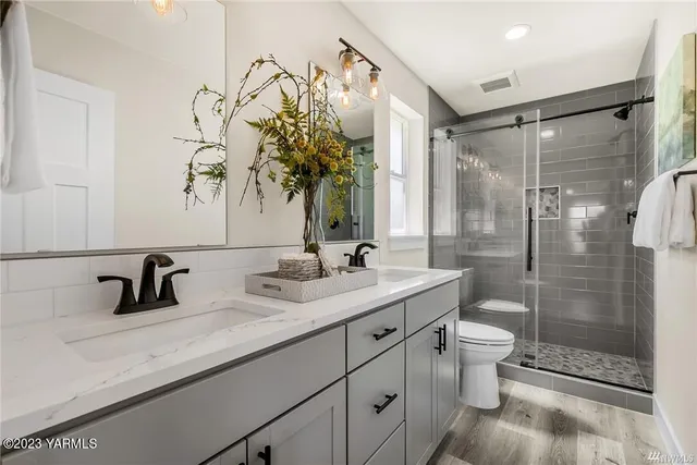 a bathroom with a double vanity sink toilet and shower
