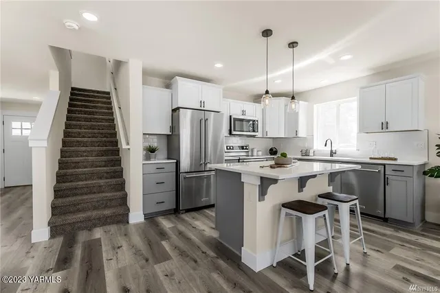 a kitchen with a refrigerator a sink and white cabinets
