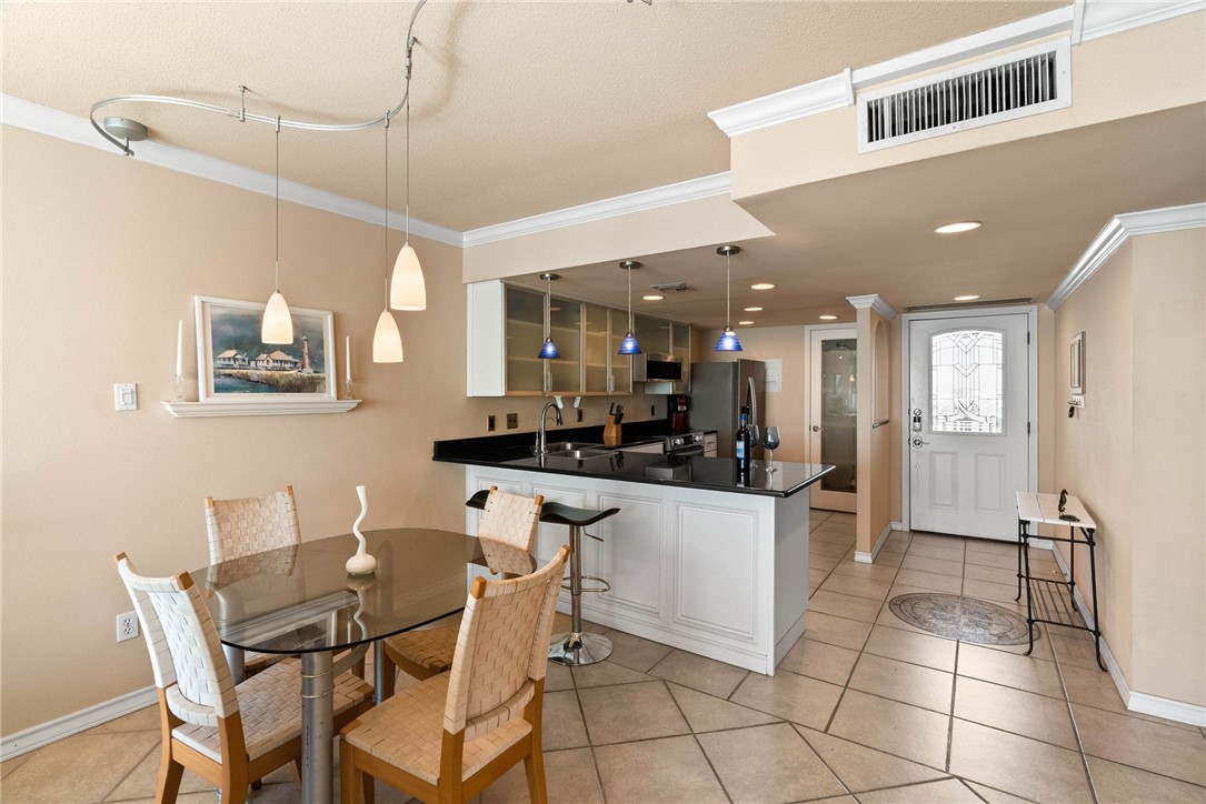 4000 Surfside Boulevard, Unit 508 Corpus Christi, TX 78402 - Photo 4 of 32 a kitchen with stainless steel appliances kitchen island granite countertop a dining table chairs and a refrigerator