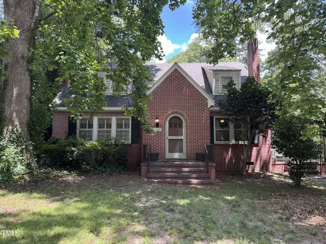 a view of a house with a yard and lawn chairs with a fire pit