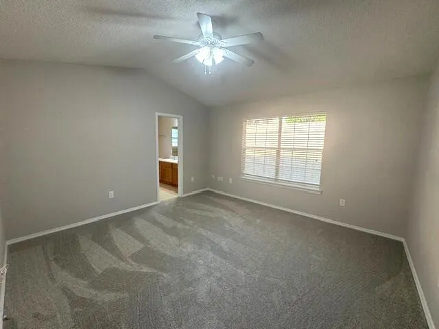 an empty room with chandelier fan and windows