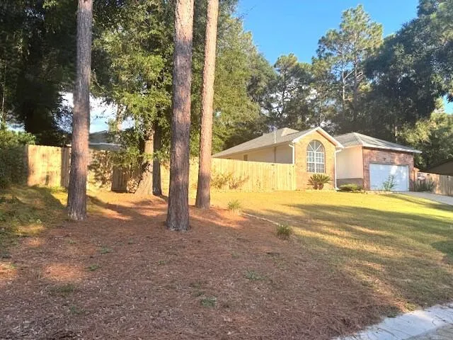 a view of a white house with a big yard and large tree