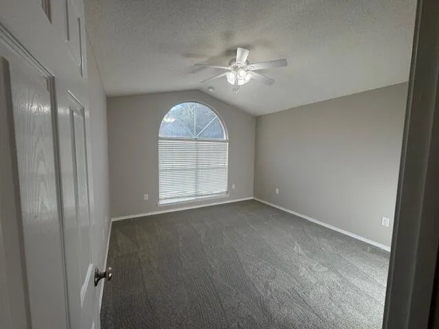 an empty room with chandelier fan and windows