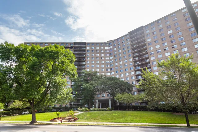 a view of a building with a yard and a large tree