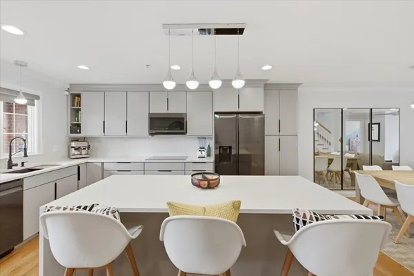 a kitchen with kitchen island a white cabinets and stainless steel appliances