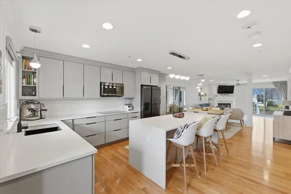 a kitchen with stainless steel appliances kitchen island granite countertop a sink a stove a refrigerator cabinets and chairs