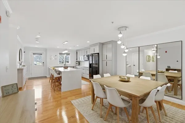 a dining hall with stainless steel appliances kitchen island a table and chairs