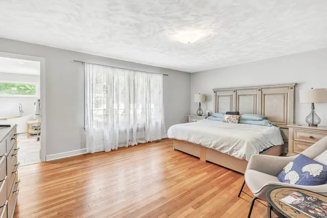 a large bed sitting in a spacious bedroom next to a window and a chair