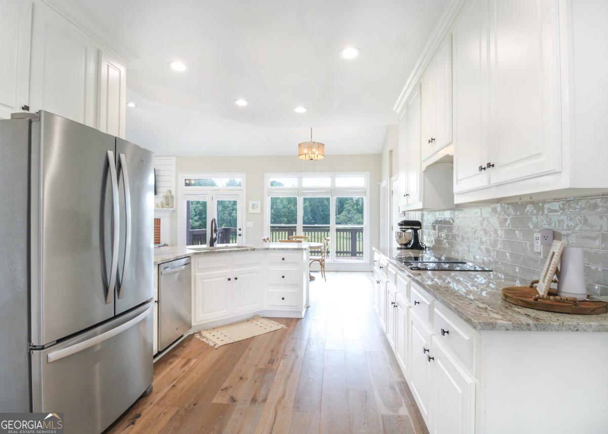 1380 Sunset Ridge Watkinsville, GA 30677 - Photo 12 of 74 a kitchen with stainless steel appliances granite countertop a refrigerator a sink dishwasher a stove and white cabinets with wooden floor