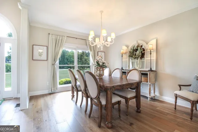 a dining room with wooden floor a chandelier a wooden table and chairs