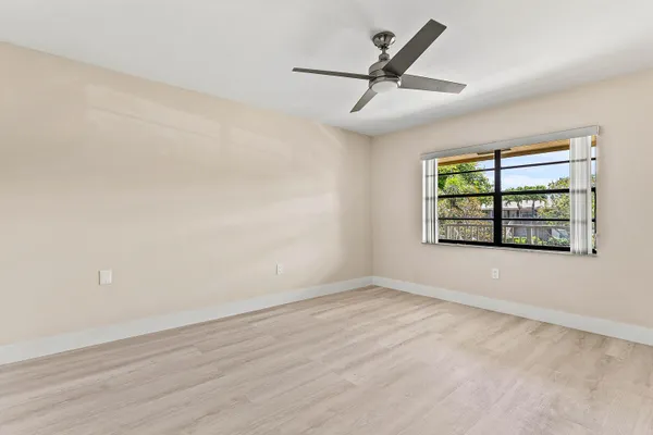 an empty room with windows and fan