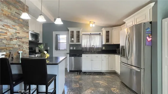 a kitchen with stainless steel appliances granite countertop a refrigerator a sink dishwasher a stove and white countertops with wooden floor