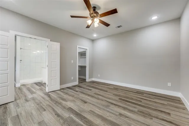 an empty room with wooden floor and ceiling fan