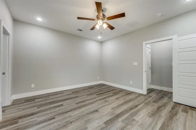 an empty room with wooden floor and ceiling fan
