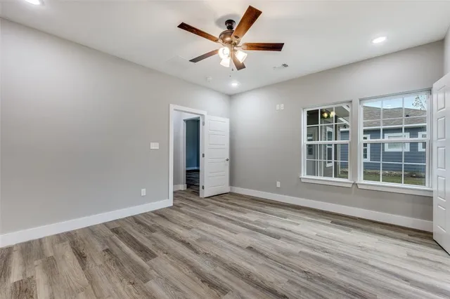 a view of an empty room with a window and wooden floor