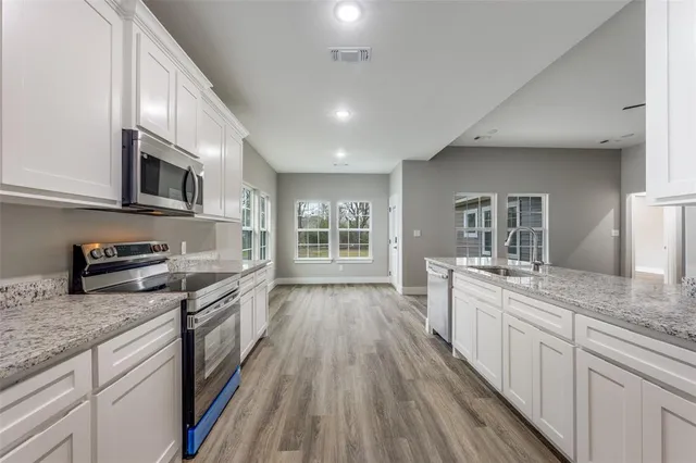 a large kitchen with granite countertop a stove top oven a sink a counter space and cabinets