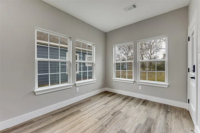 a view of an empty room with wooden floor and windows