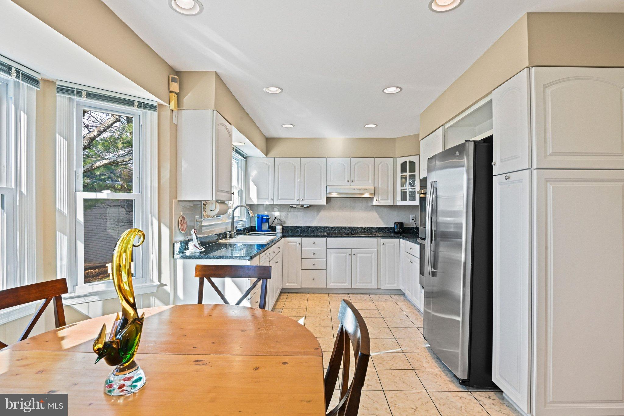 2707 Glencroft Road Vienna, VA 22181 - Photo 19 of 53 a kitchen with stainless steel appliances granite countertop a refrigerator a stove a sink dishwasher with a dining table and chairs