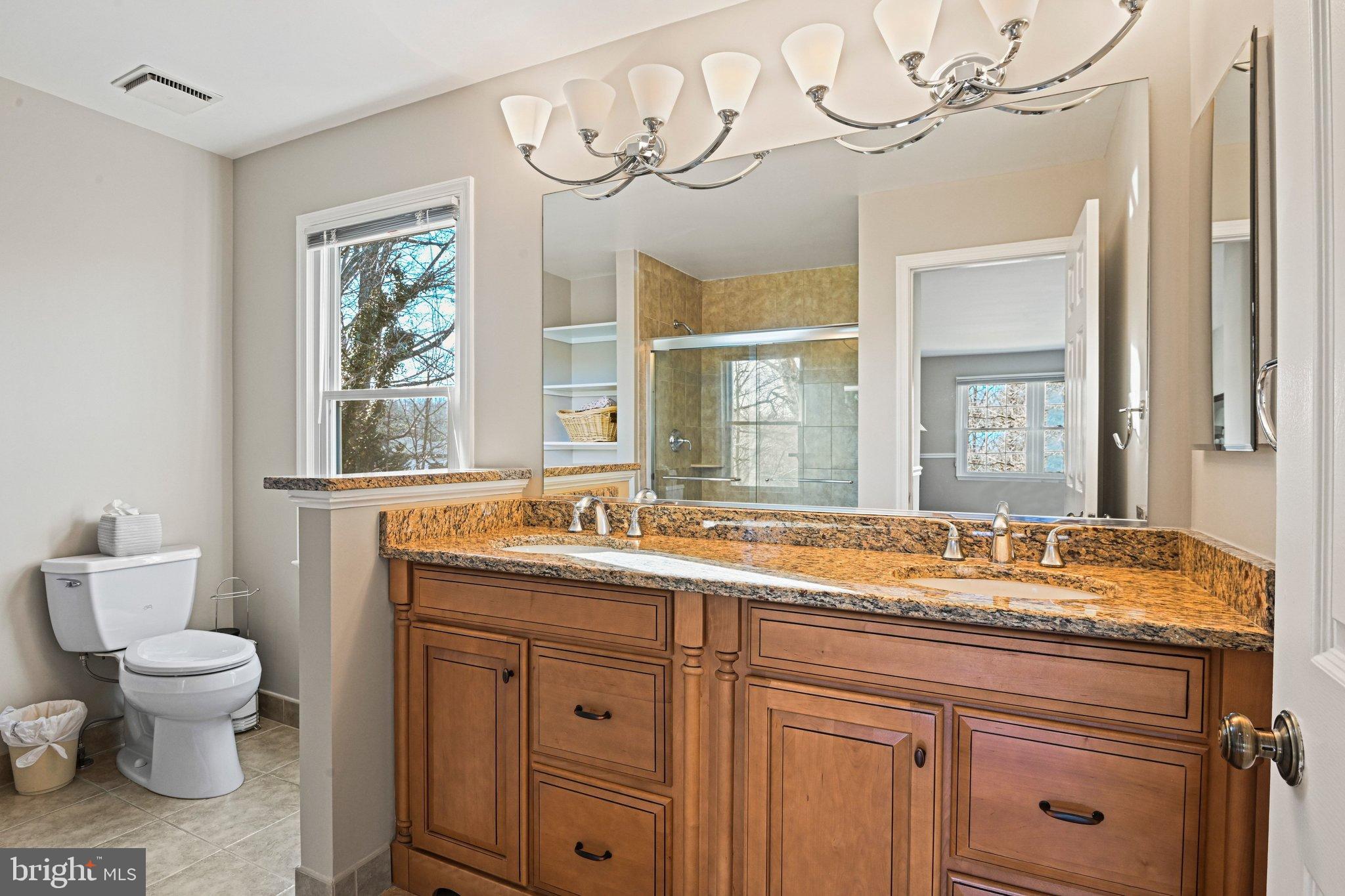 2707 Glencroft Road Vienna, VA 22181 - Photo 31 of 53 a bathroom with a granite countertop toilet a sink and a large mirror