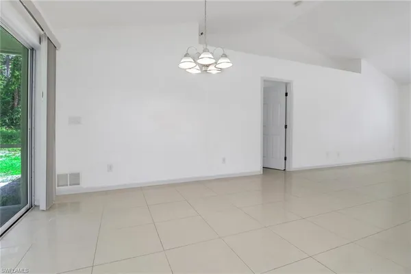 a view of an empty room with a chandelier fan