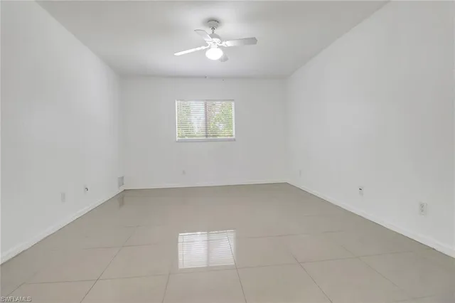an empty room with a window and a ceiling fan