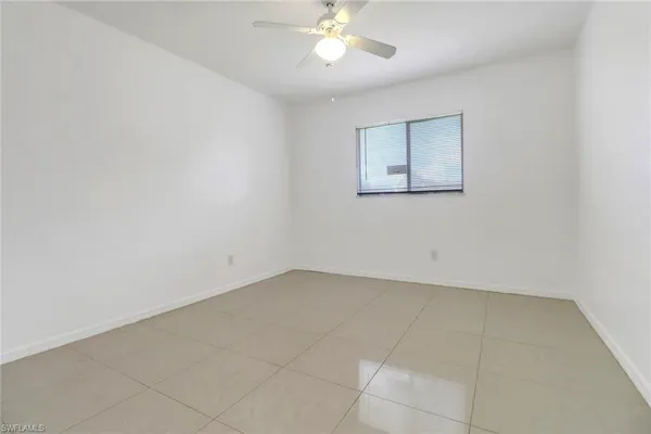 an empty room with a chandelier fan and windows