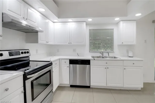 a kitchen with stainless steel appliances white cabinets and a stove top oven