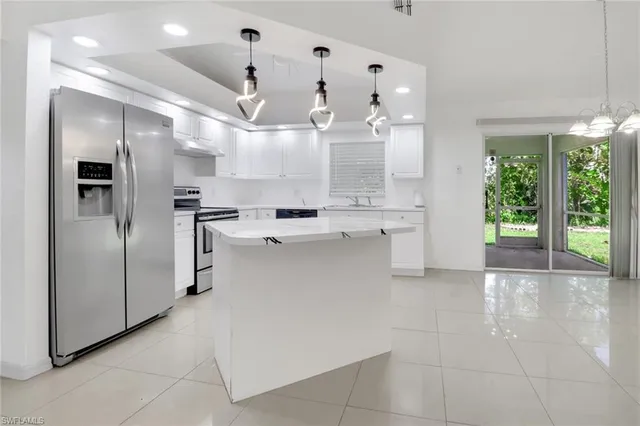a kitchen with stainless steel appliances kitchen island granite countertop a refrigerator and a sink
