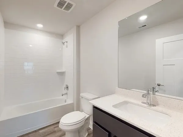 a bathroom with a granite countertop sink a toilet and shower