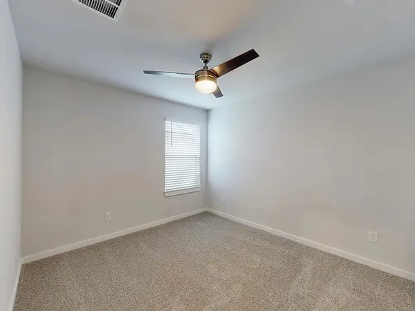 an empty room with windows and fan