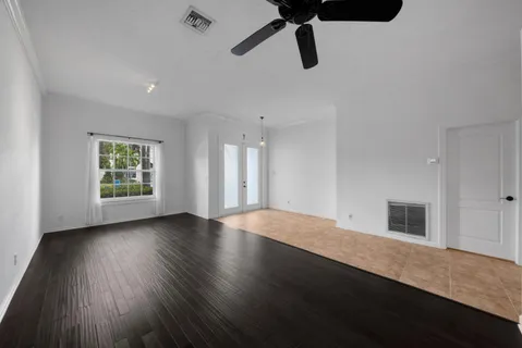 a view of empty room with wooden floor and fan