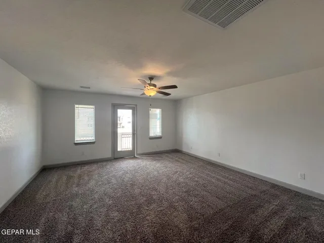 an empty room with windows and fan