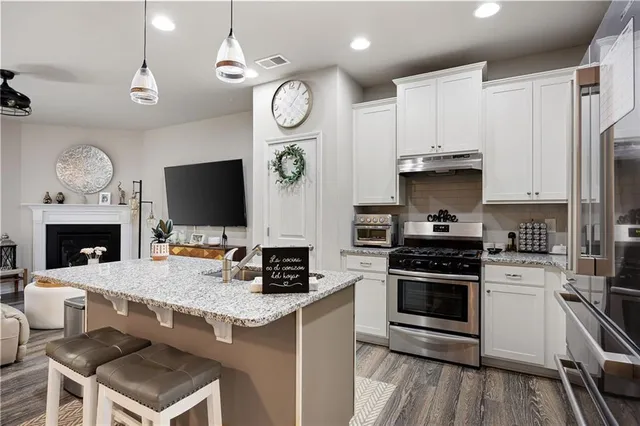 a kitchen with granite countertop a stove top oven a clock and cabinets