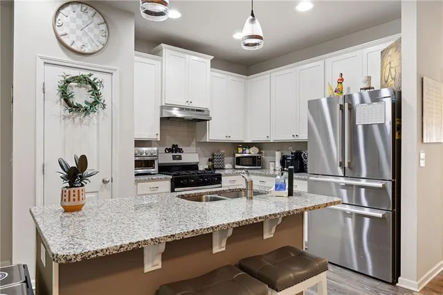 a kitchen with stainless steel appliances granite countertop a sink a stove and refrigerator