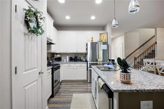 a kitchen with stainless steel appliances granite countertop a sink a stove and a refrigerator