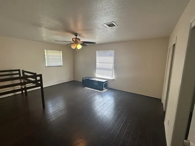 a view of empty room with wooden floor and fan