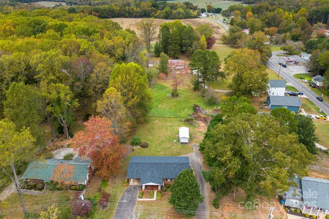 an aerial view of residential houses with outdoor space and trees