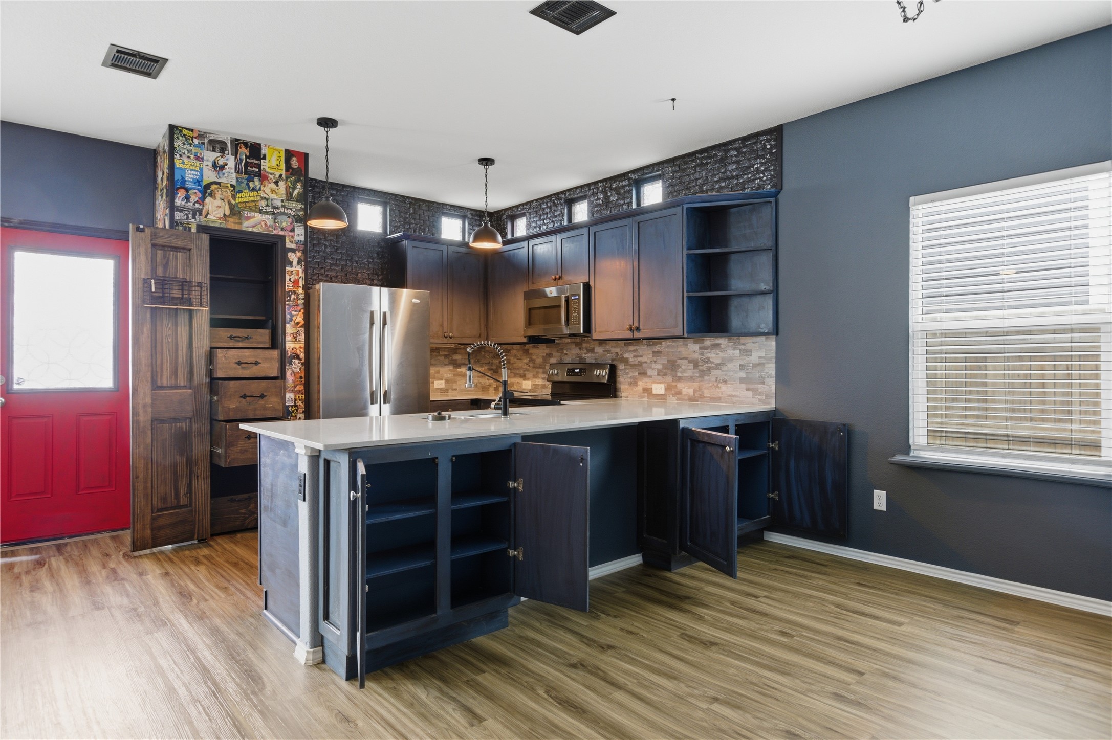 116 Night Riders Way Jarrell, TX 76537 - Photo 13 of 40 Modern kitchen featuring a central island with integrated storage, dark cabinetry, and a mosaic tile backsplash