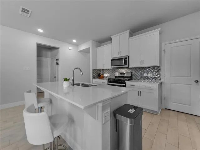 a large white kitchen with a sink and dishwasher stove top oven