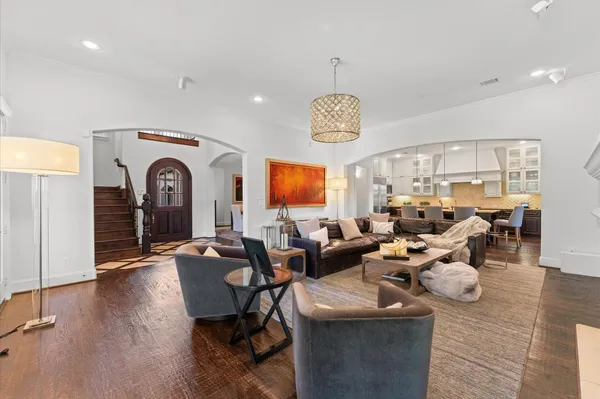a living room with lots of furniture kitchen view and a chandelier