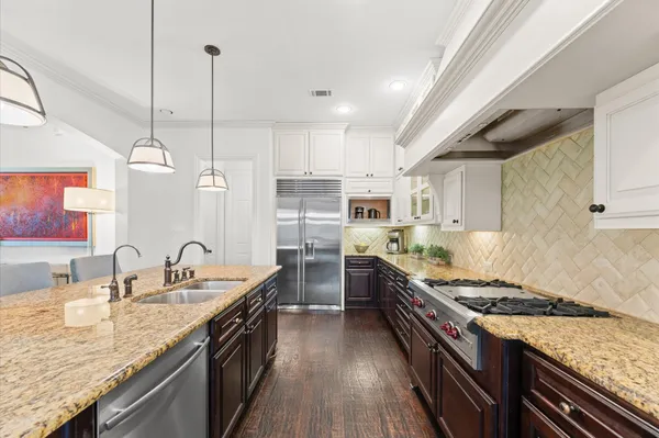 a kitchen with stainless steel appliances granite countertop a stove a sink dishwasher a refrigerator and a oven with wooden floor