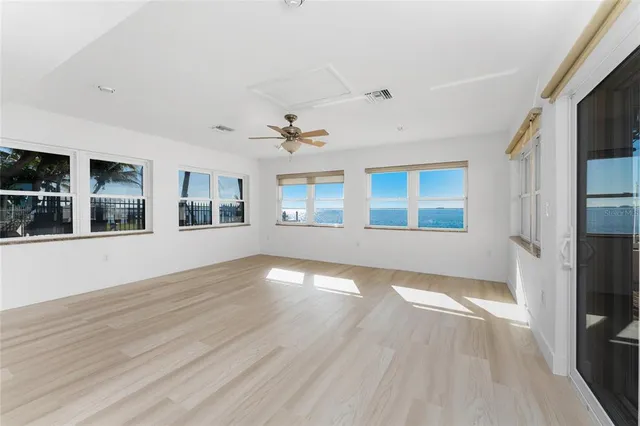 an empty room with wooden floor chandelier fan and windows