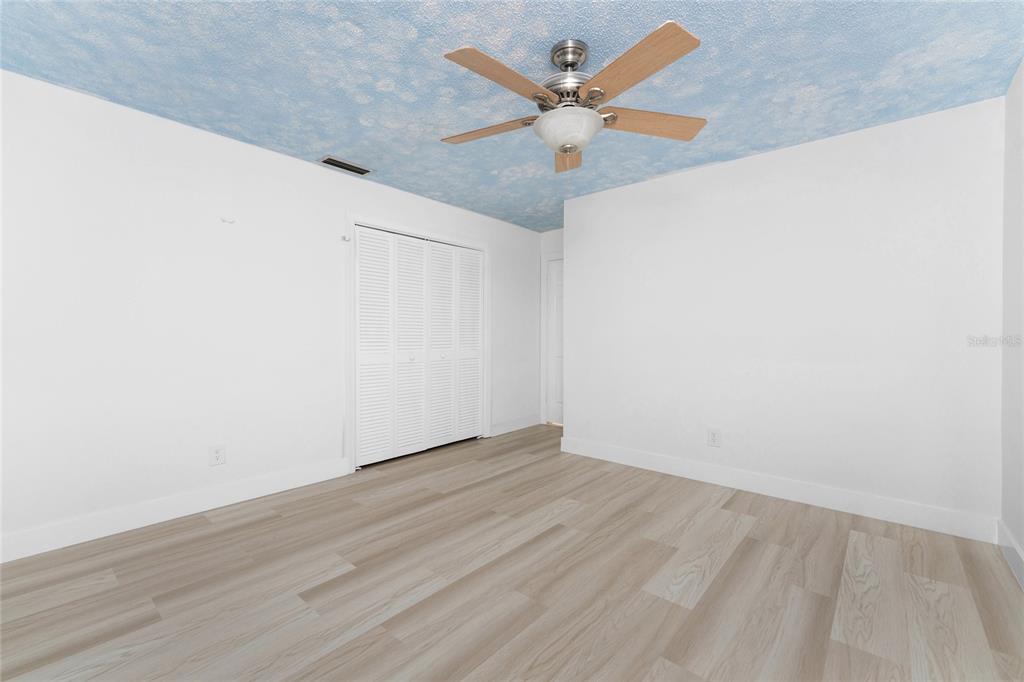 341 Severin Road Southeast Port Charlotte, FL 33952 - Photo 44 of 90 an empty room with wooden floor and a fan