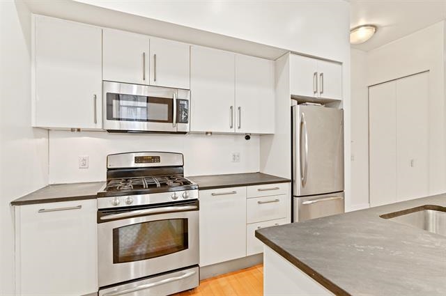 4 Beacon Way, Unit 222 Jersey City, NJ 07304 - Photo 4 of 20 a kitchen with cabinets stainless steel appliances and a counter space