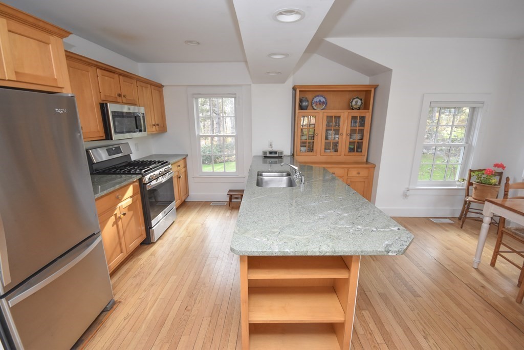 344 Flat Hills Road Amherst, MA 01002 - Photo 20 of 42 a kitchen with stainless steel appliances granite countertop a stove a refrigerator a sink a dining table and chairs with wooden floor