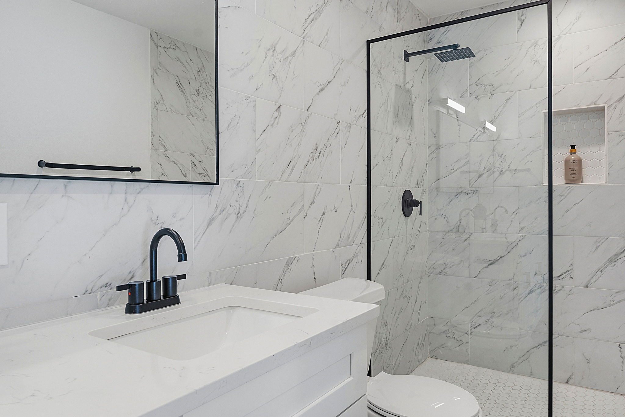 4403 Elmsgrove Drive Austin, TX 78721 - Photo 34 of 38 Modern bath features a sleek vanity, black fixtures, and a shower with tile-patterned walls.