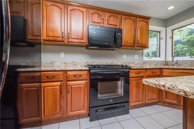 a kitchen with granite countertop a stove top oven microwave and cabinets